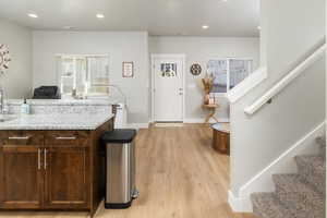 Kitchen with light wood-type flooring, light stone countertops, and sink