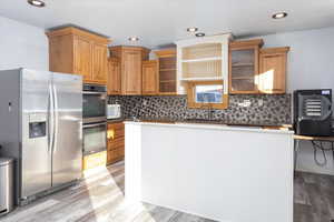 Kitchen featuring light wood-type flooring, stainless steel appliances, backsplash, and sink