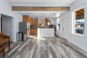 Kitchen with hardwood / wood-style flooring, stainless steel fridge, tasteful backsplash, and beamed ceiling