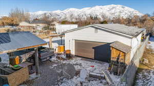 Snow covered property with an outbuilding, a mountain view, and a garage