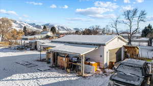 Snow covered property with a garage, a mountain view, and an outdoor structure