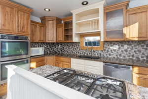 Kitchen with wood-type flooring, decorative backsplash, sink, appliances with stainless steel finishes, and dark stone counters