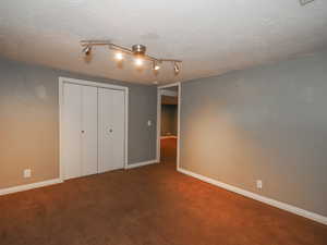 Unfurnished bedroom featuring carpet, a closet, and a textured ceiling