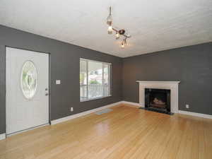 Foyer featuring a textured ceiling, light hardwood / wood-style flooring, and a tiled fireplace