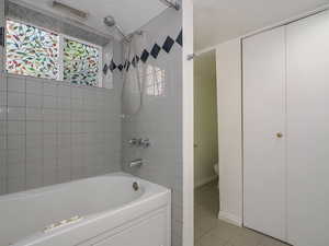 Bathroom featuring tile patterned floors, tiled shower / bath combo, and toilet