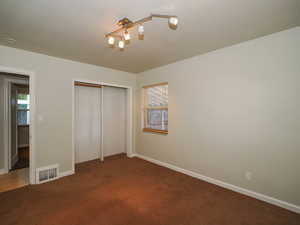 Unfurnished bedroom with a closet and dark colored carpet