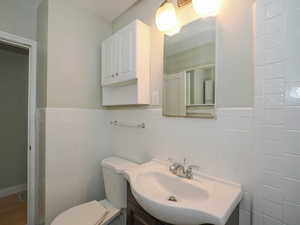 Bathroom with toilet, tile walls, and vanity