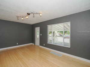 Spare room with a textured ceiling and light hardwood / wood-style floors