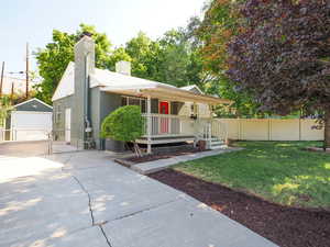 View of front of house featuring covered porch, central AC unit, a garage, a front yard, and an outdoor structure