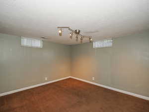 Basement featuring a textured ceiling and carpet