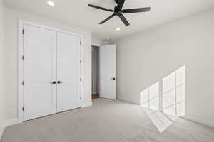 Unfurnished bedroom with ceiling fan, light colored carpet, and a closet