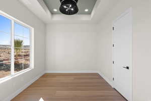 Entry room/bedroom featuring light hardwood / wood-style floors and a raised ceiling