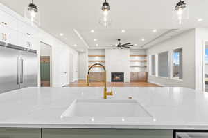 Kitchen featuring stainless steel appliances, a raised ceiling, light stone countertops, pendant lighting, and sink