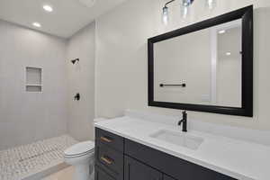 Bathroom featuring toilet, vanity, tile patterned floors, and a tile shower