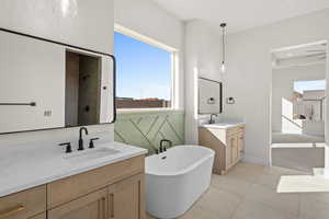 Primary bathroom featuring ceiling fan, tile patterned floors, vanity, and separate shower and tub