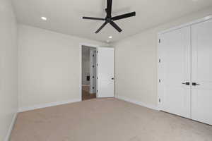 Bedroom featuring light carpet, ceiling fan, and a closet