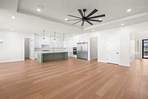 Kitchen featuring white cabinetry, an island with sink, appliances with stainless steel finishes, tasteful backsplash, and hanging light fixtures