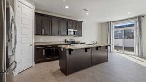 Kitchen featuring a center island with sink, sink, a kitchen breakfast bar, stainless steel appliances, and light stone counters