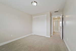 Unfurnished bedroom with a closet and light carpet