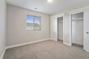 Unfurnished bedroom with light carpet and multiple closets