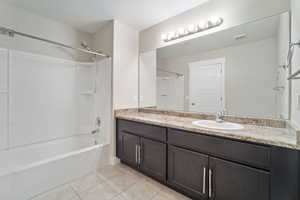 Bathroom featuring shower / bathing tub combination, vanity, and tile patterned flooring