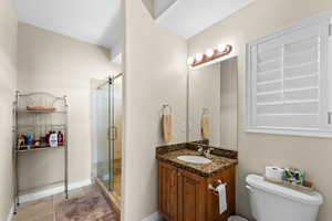 Bathroom featuring tile patterned flooring, toilet, a shower with door, and vanity