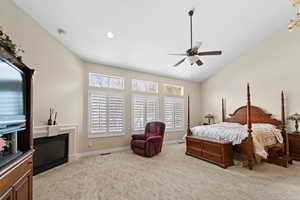 Carpeted bedroom with ceiling fan and lofted ceiling