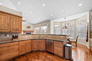 Kitchen featuring kitchen peninsula, dishwasher, backsplash, and stone countertops