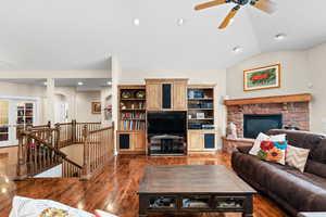 Living room with lofted ceiling, dark wood-type flooring, french doors, a fireplace, and ceiling fan