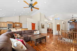 Living room featuring ceiling fan, dark wood-type flooring, and high vaulted ceiling