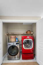 Laundry area featuring tile patterned floors and washer and clothes dryer