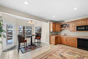 Kitchen with black appliances, decorative light fixtures, sink, a notable chandelier, and light tile patterned flooring