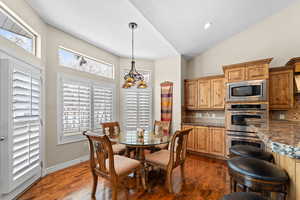 Dining area with vaulted ceiling, dark hardwood / wood-style flooring, an inviting chandelier, and a textured ceiling