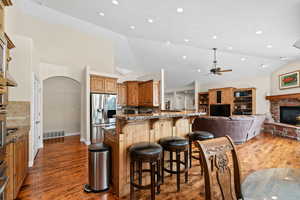 Kitchen featuring lofted ceiling, stainless steel appliances, a fireplace, backsplash, and a breakfast bar area