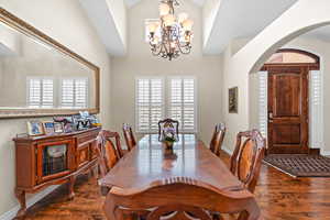 Dining room with high vaulted ceiling, dark hardwood / wood-style floors, and a notable chandelier