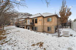 Snow covered back of property featuring a deck with mountain view