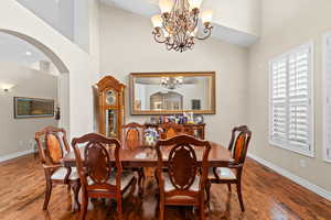 Dining space with a high ceiling, an inviting chandelier, and hardwood / wood-style flooring