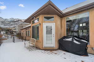 Snow covered deck featuring a mountain view and area for grilling