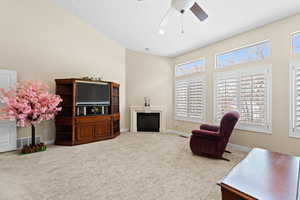 Living room with ceiling fan, a towering ceiling, and carpet flooring