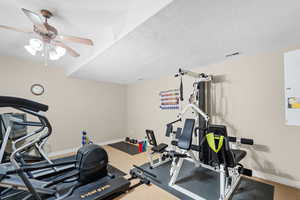 Workout area with ceiling fan, carpet, and a textured ceiling