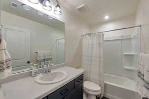 Full bathroom featuring shower / bath combo with shower curtain, toilet, and vanity