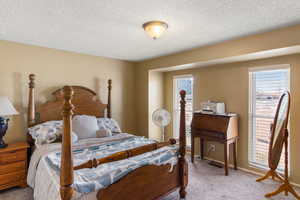 Bedroom featuring light colored carpet and a textured ceiling