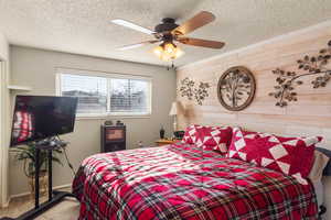 Bedroom featuring a textured ceiling, ceiling fan, carpet, and wood walls