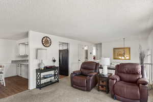 Carpeted living room with a textured ceiling and a chandelier