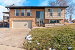 Bi-level home featuring a garage and a front yard