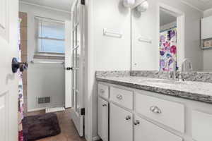 Bathroom featuring vanity, ornamental molding, and tile patterned flooring