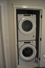 Washroom with stacked washer / drying machine and tile patterned floors