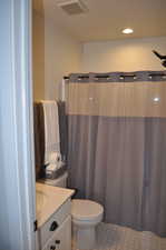 Bathroom featuring toilet, tile patterned flooring, vanity, and curtained shower