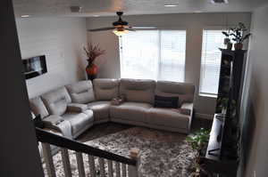 Living room with ceiling fan, wood-type flooring, and a textured ceiling