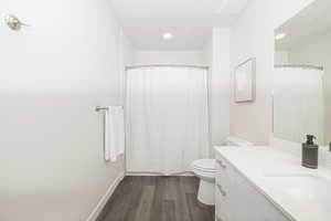 Bathroom with hardwood / wood-style flooring, toilet, and vanity